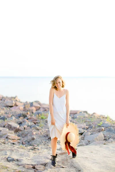 Bella donna che cammina sulla spiaggia di ghiaia con hant in mano e indossa vestito . — Foto Stock