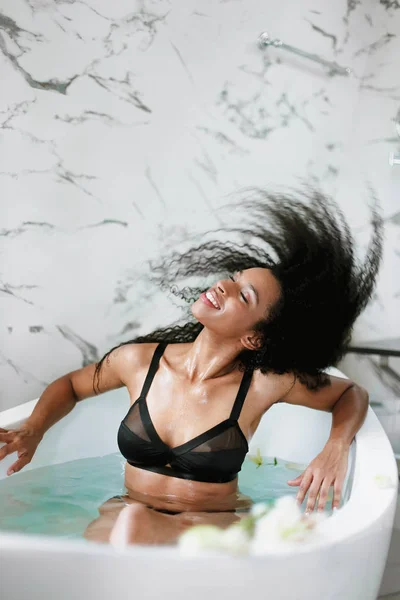 Young jocund girl taking bath and wearing black swimsuit. — Stock Photo, Image