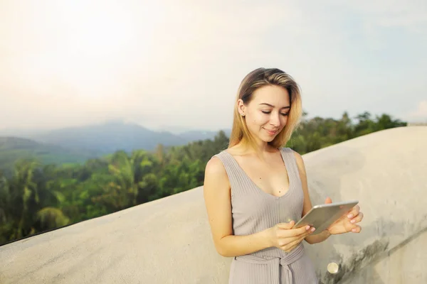 Young blonde girl using tablet with mountains background, Thailand. — Stock Photo, Image