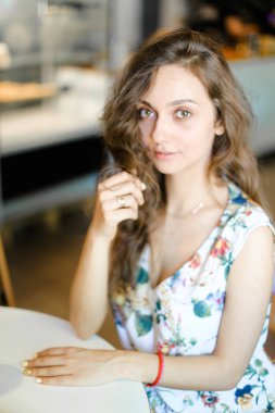 Kafede oturan ve kıvırcık saç dokunmadan genç büyüleyici öğrenci.