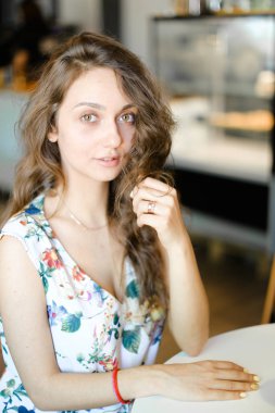 Kafede oturan ve kıvırcık saç dokunmadan genç sevimli öğrenci.