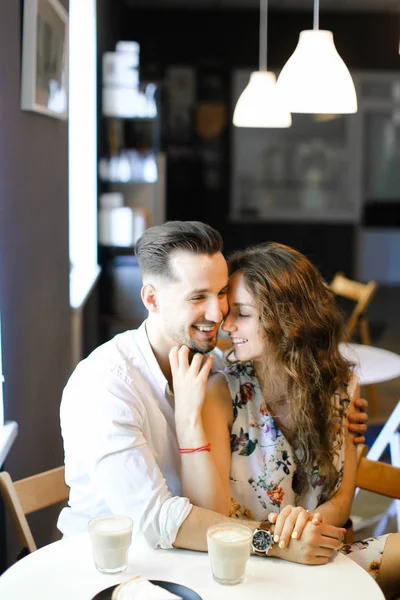 Jovem casal feliz sentado no café e abraçando . — Fotografia de Stock