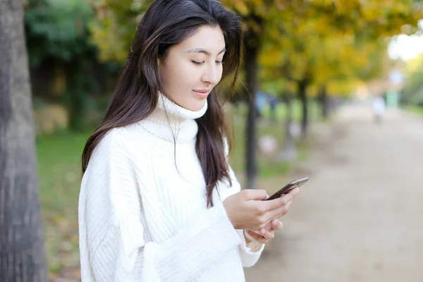 Chica coreana usando smartphone y caminando en el parque . — Foto de Stock