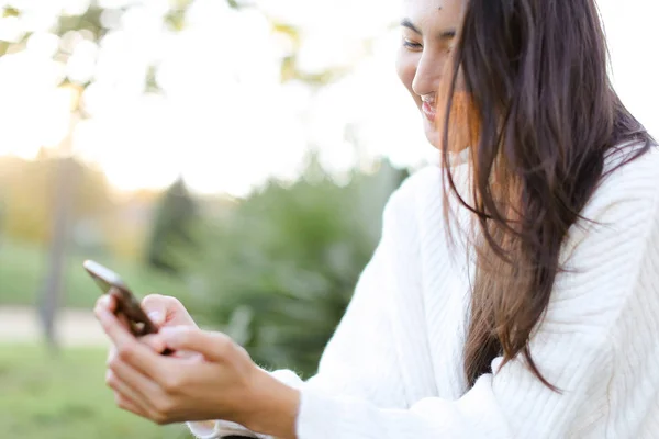 Concéntrate en la chica china manteniendo el teléfono inteligente y sonriendo . — Foto de Stock