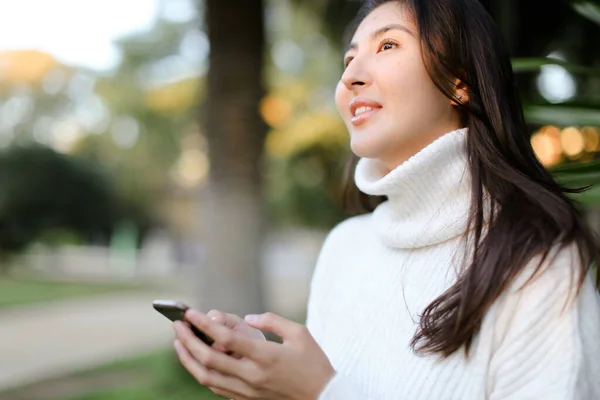 Chica linda china usando teléfono inteligente y caminando en el parque tropical . — Foto de Stock