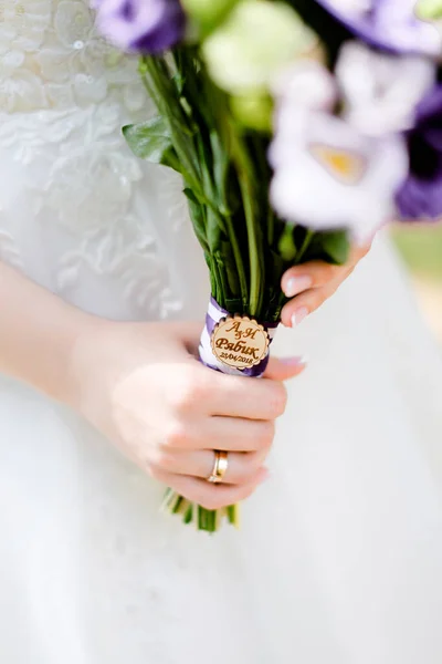 Closeup bridal hands keeping bouquet of flowers.