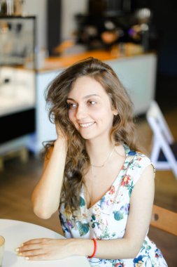 Kafede oturan ve kıvırcık saç dokunmadan genç güzel öğrenci.