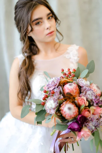 Πορτρέτο της νεαρής καυκάσιας μελαχρινής νύφης με λουλούδια στο φωτογραφείο. — Φωτογραφία Αρχείου