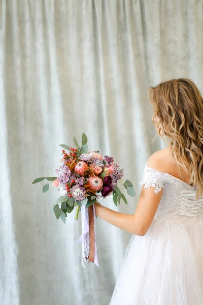 Πίσω όψη της νεαρής καυκάσιας νύφης που στέκεται στο φωτογραφείο με λουλούδια. — Φωτογραφία Αρχείου