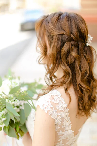 Visão traseira de cachos agradáveis cabelo fazer para noiva mantendo flores . — Fotografia de Stock