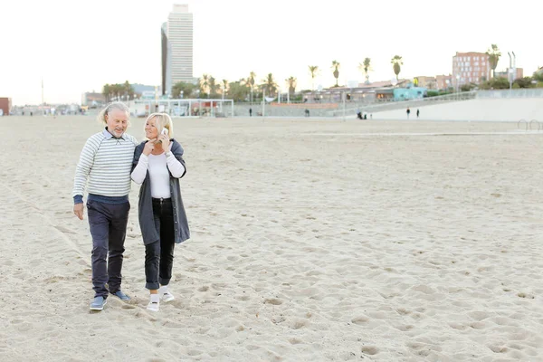 Séta a homokos strand, szőke felesége beszél a smartphone vezető férje. — Stock Fotó