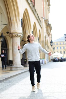 Genç çocuk Avrupa'nın meydanında yürüyüş gri kazak giyiyor.