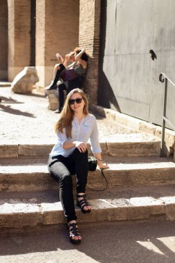 Colosseum, İtalya içinde merdivenlerde oturan genç kadın turist.