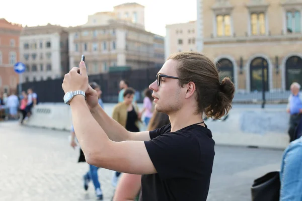 Giovane turista caucasico maschio che scatta foto da smartphone di edifici europei in Italia . — Foto Stock