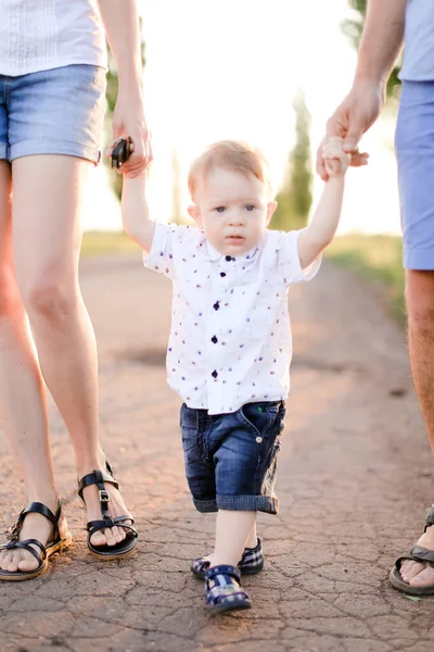 Bambino maschio che tiene per mano i genitori e cammina sulla strada . — Foto Stock