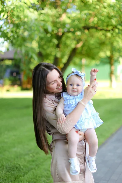 Giovane madre caucasica che tiene piccolo bambino femminile in giardino . — Foto Stock