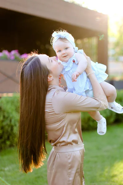 Young caucasian woman holding and kissing little daughter. — Stock Photo, Image