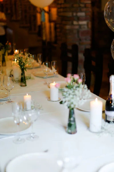 Ramo de flores, platos blancos y velas en la mesa . — Foto de Stock