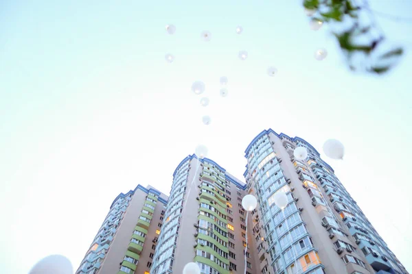 Edificio alto y volar globos blancos en el fondo del cielo . — Foto de Stock