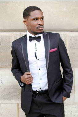 Siyah takım elbiseli ve binanın yanında duran başarılı Afro-Amerikan adam..