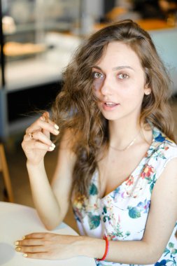 Kafede oturan ve kıvırcık saçlı dokunmadan Genç beyaz öğrenci.