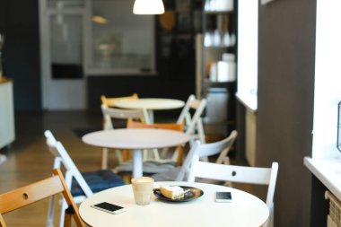 Bardak kahve, akıllı telefonlar ve pasta masada boş rahat kafe.