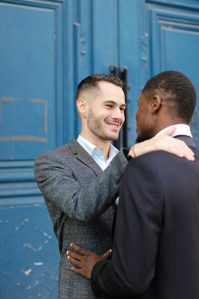 Caucasian man hugging afro american boy in door background.