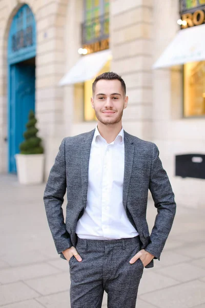 Joven hombre de cacuasia vestido de traje de pie cerca del edificio exterior . — Foto de Stock