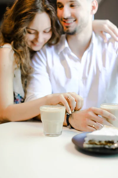 Mujer joven abrazando al hombre y sentado en la cafetería . — Foto de Stock