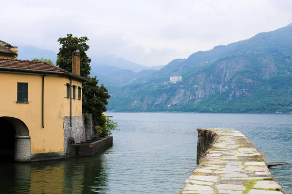 Casa sul lago di Como acqua, montagna sullo sfondo . — Foto Stock