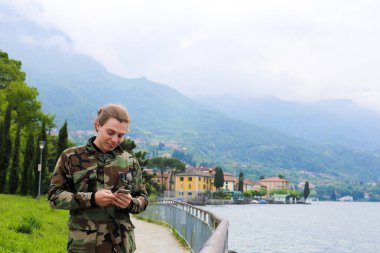 Arka planda Como Gölü ve Alps Dağı 'nda akıllı telefondan sohbet eden genç adam var..
