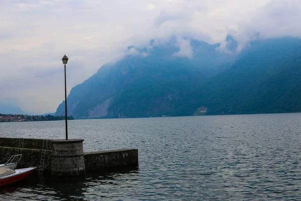 船口岸与灯笼在科莫湖在 Madlello del 拉里奥, 蓝色阿尔卑斯山与云彩在背景上. — 图库照片