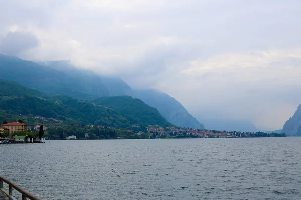 Sahil şeridi üzerinde binalar, Alpler Dağı ile arka planda bulutlar ile Como Gölü. — Stok fotoğraf