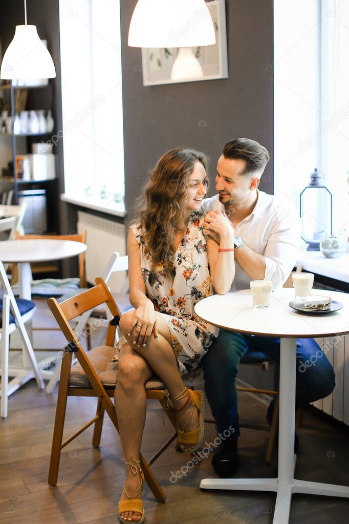 Young happy caucasian couple sitting at cafe and resting.