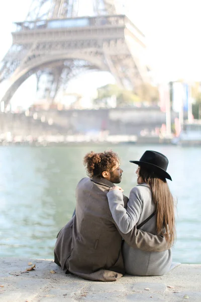 Afro amerikai férfi ölelés lány kalap és ül közel Eiffel torony, Párizs. — Stock Fotó