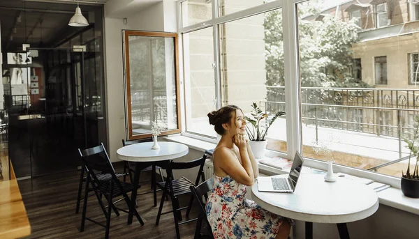 Junges kaukasisches Mädchen sitzt mit Laptop im Café. — Stockfoto