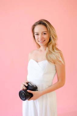 Pembe monoponik arka planda kameralı genç Avrupalı kadın fotoğrafçı.