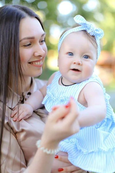 Primo piano felice madre sorridente che tiene piccolo bambino femmina in abito blu . — Foto Stock