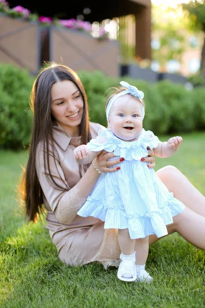 Giovane madre seduta sull'erba con piccola figlia . — Foto Stock