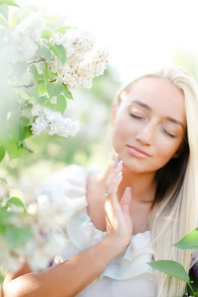 Närbild ansikte av blond kvinna med slutna ögon och vita lila blommor. — Stockfoto