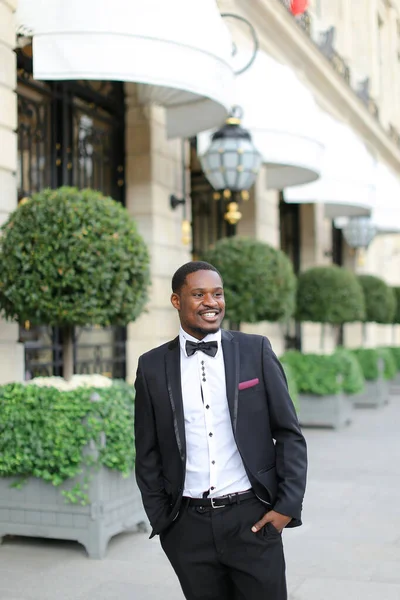 Afroamerikaner lächelt im Anzug und steht in der Nähe des Gebäudes. — Stockfoto