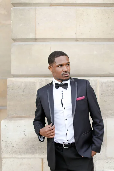 Afroamerikanischer erfolgreicher Mann trägt dunklen Anzug und steht im Freien an der Wand. — Stockfoto