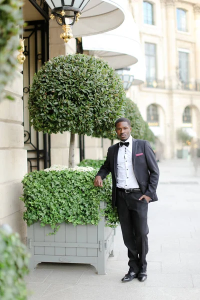 Afroamerikanische männliche Person trägt Anzug und steht neben Baum in der Stadt. — Stockfoto