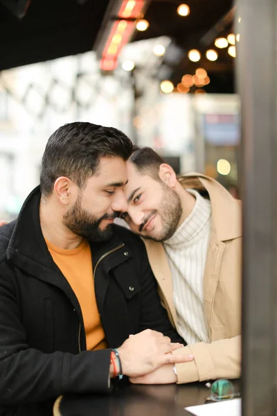 Zwei glückliche kaukasische Schwule sitzen und umarmen sich und halten die Hände. — Stockfoto