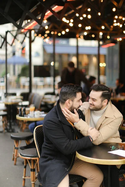 Blank gelukkig homo 's zitten bij cafe en knuffelen. — Stockfoto