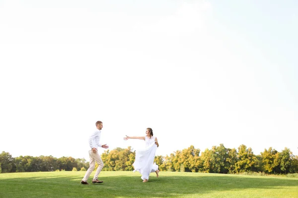 Noivo e noiva feliz correndo e jogando na grama . — Fotografia de Stock