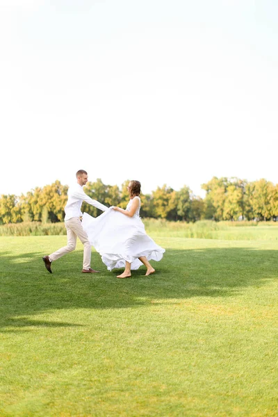 Mariée et marié courent et dansent sur l'herbe . — Photo