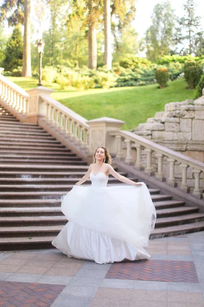 Mooie bruid in wite jurk in de buurt van betonnen trap. — Stockfoto
