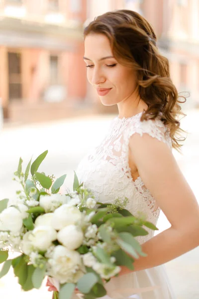 Happy nice pengantin menjaga karangan bunga dan mengenakan gaun putih . — Stok Foto