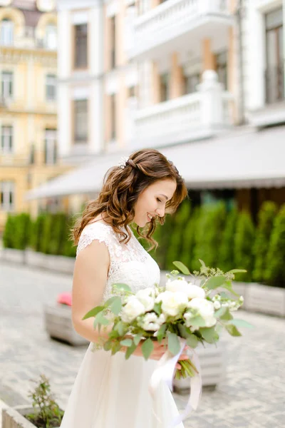 Pengantin wanita bahagia kaukasia berjalan dengan karangan bunga di kota . — Stok Foto